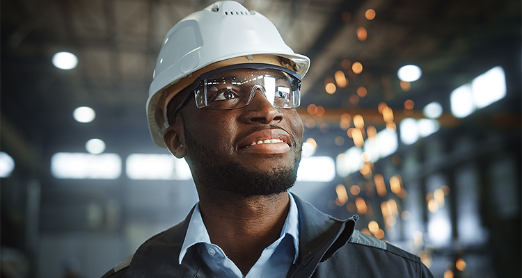 Person of colour in construction hat and safety glasses